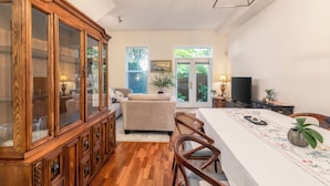 A dining area with a wooden cabinet, a sofa, a television, and a dining table with chairs. - Central 3BR Townhouse  Near Oakridge & SkyTrain to Airport & BC Place (Vancouver)