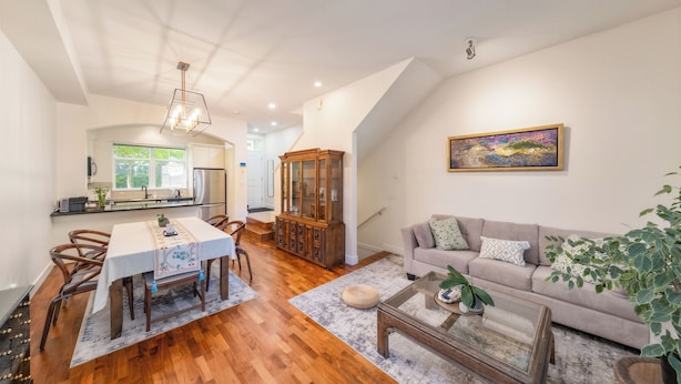A spacious living area with a dining table, sofa, and a large cabinet. - Central 3BR Townhouse  Near Oakridge & SkyTrain to Airport & BC Place (Vancouver)