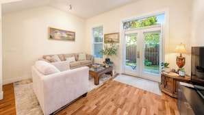 A living room with a sofa, coffee table, and a lamp. There is a sliding glass door leading to a garden. - Central 3BR Townhouse  Near Oakridge & SkyTrain to Airport & BC Place (Vancouver)
