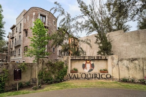 En byggnad med en skylt som visar texten ”VAL’QUIRICO” och en stenmur med ett vapensköld.
