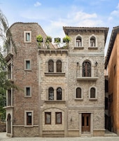 Un edificio de varios pisos con fachadas de piedra, ventanas en arco y balcones.