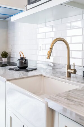 A kitchen with a modern faucet, a kettle, and a marble countertop. - Loft Encantador y Elegante ValQuirico (Tetlatlahuca)