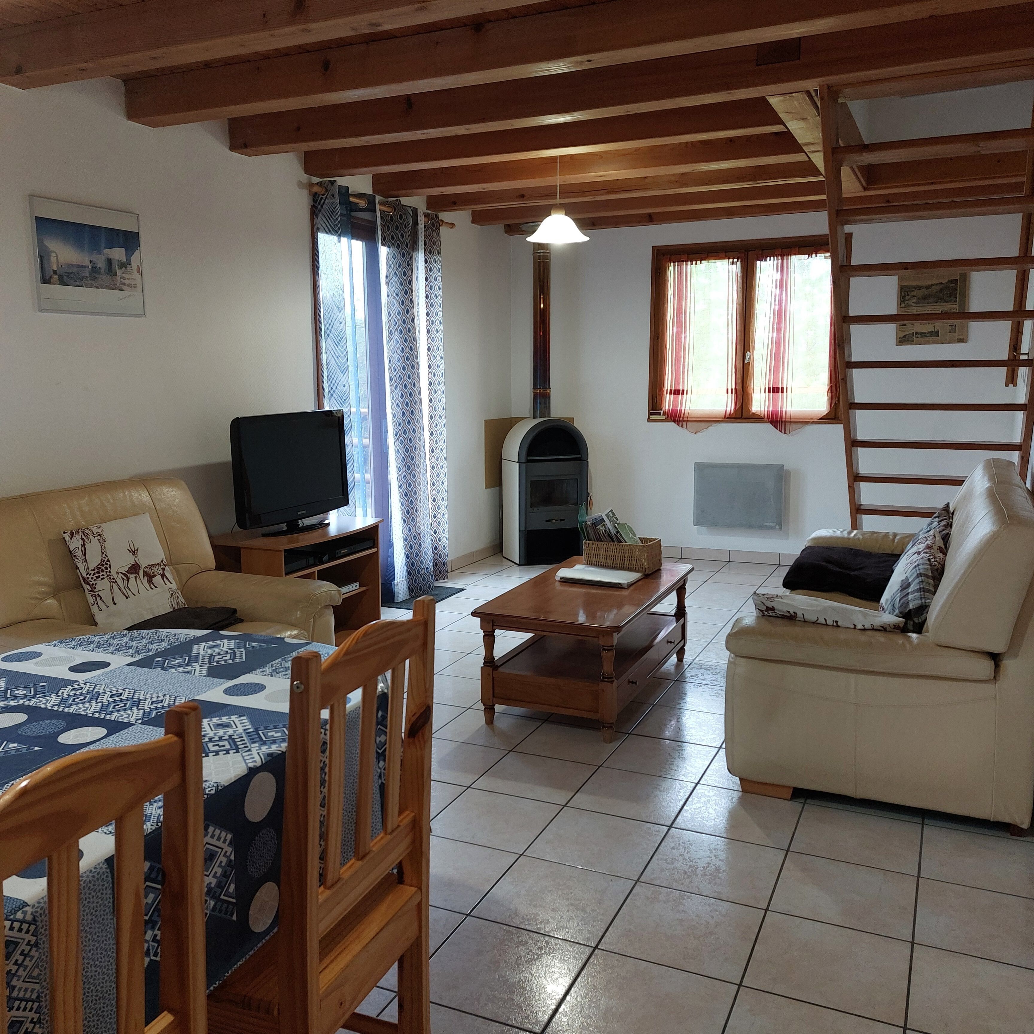 Una sala de estar con un sofá, una mesa de madera, un televisor, una chimenea y una ventana con cortinas.