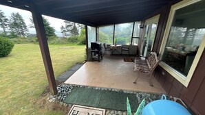 Un patio techado con una parrilla, asientos y vistas al exterior.