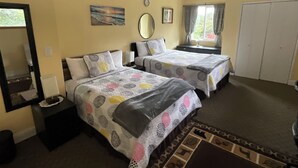 Habitación de hotel con dos camas, un espejo, un cuadro, un reloj, una ventana con cortinas y un armario.