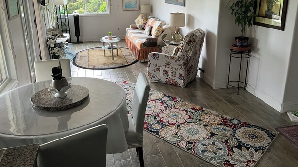 Una sala de estar con una mesa redonda, un sofá, una silla, una lámpara y una planta en maceta.