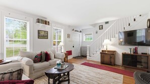 A living room with a sofa, a coffee table, a TV, and a staircase. - Historic Gem in the Heart of Littleton (Littleton)