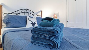 A neatly made bed with a blue quilt and pillows, a folded blanket, and a deer-themed pillow on a metal headboard. - Historic Gem in the Heart of Littleton (Littleton)