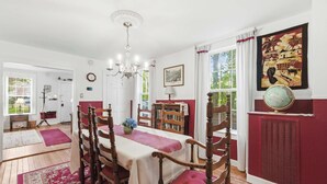 A dining room with a table set for four, wooden chairs, a chandelier, and a globe on the wall. - Historic Gem in the Heart of Littleton (Littleton)