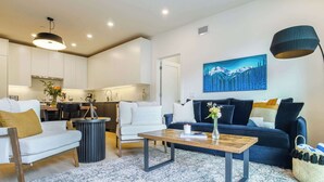 Uma sala de estar moderna com sofá, mesa de centro e um quadro na parede.