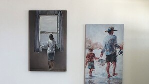 A room with two wooden chairs, a small wicker stool, and two paintings on the wall. - Celia amazing view at the port of Adamas (Adamantas)