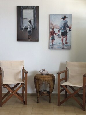 Ein Zimmer mit zwei Holzstühlen, einem kleinen Korbsitz und zwei Bildern an der Wand.