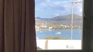 A room with a view of a body of water, a sofa, and a window with curtains. - Celia amazing view at the port of Adamas (Adamantas)