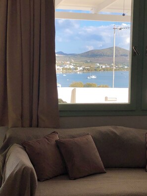 Ein Zimmer mit Blick auf ein Gewässer, einer Couch und einem Fenster mit Vorhängen.