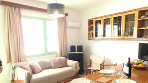 A cozy living room with a sofa, a dining table set for two, and a kitchen area with cabinets and a television. - Celia amazing view at the port of Adamas (Adamantas)