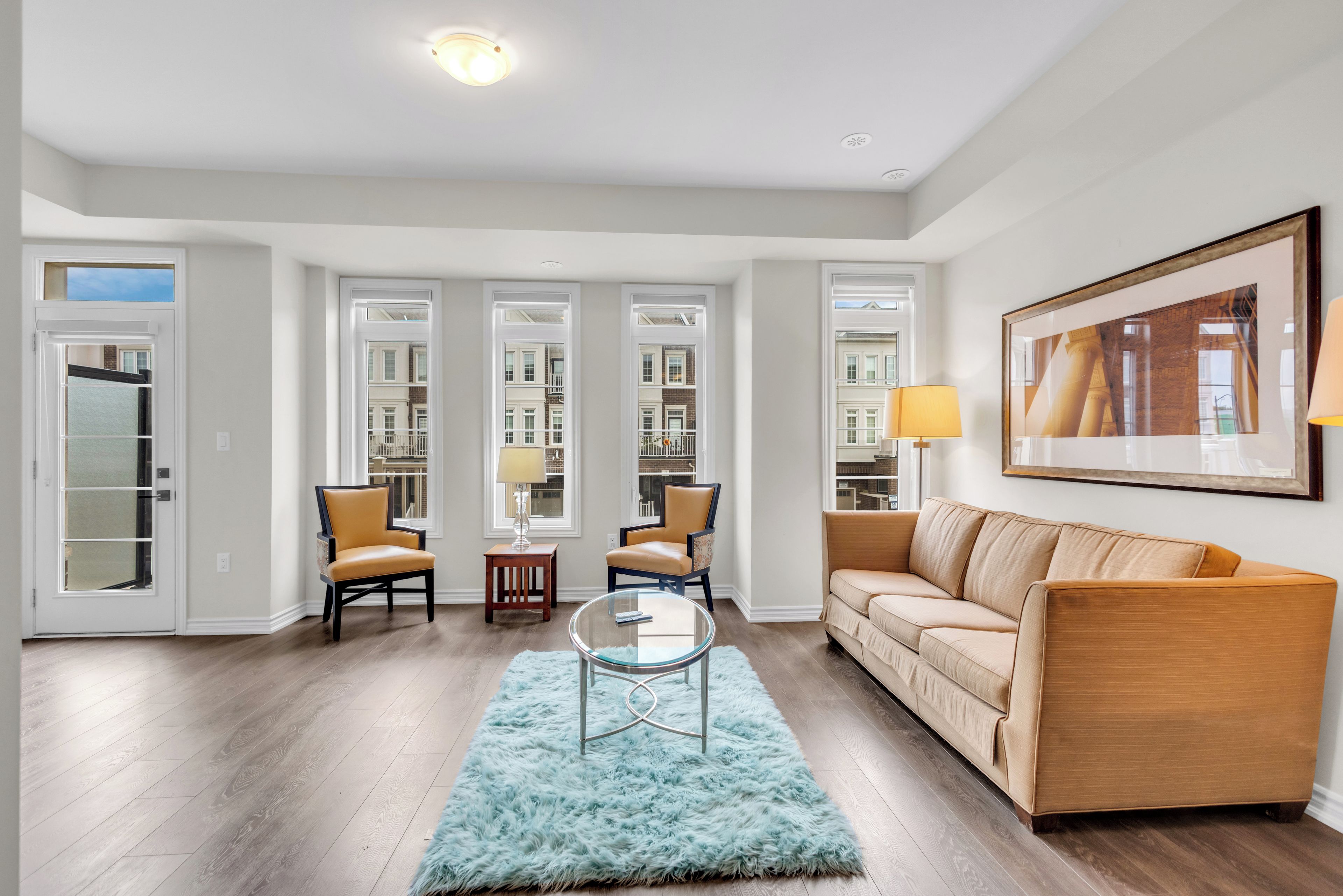 Een moderne woonkamer met een beige bank, twee fauteuils, een glazen salontafel en een zacht tapijt.