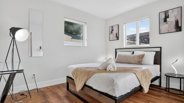 Een moderne slaapkamer met een bed, een staande lamp en een raam met uitzicht.