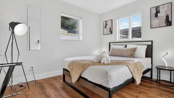 Un dormitorio moderno con una cama, una lámpara de pie y una ventana con vistas.