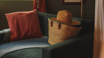 Una habitación con un sofá verde, una cesta de mimbre con un sombrero y cuadros en la pared.