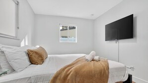 Een moderne slaapkamer met een bed, een televisie en een raam.