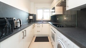 Een moderne keuken met een wasmachine, een broodrooster en een spoelbak.