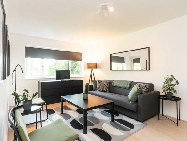 Ein modernes Wohnzimmer mit Sofa, Couchtisch und Fernseher.