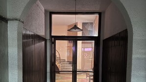 A hallway with a checkered floor, an arched ceiling, and a view into a room with a bed and a chair. - Quiet Designer Home, 2BR, Sunset Balcony • Kypseli (Athina)