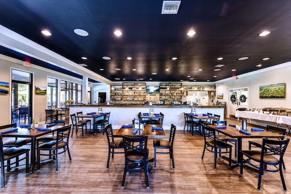 A restaurant with multiple tables and chairs, a bar area, and a view of the outdoors.
