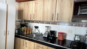 Et køkken med træskabe, en sort bordplade, en vask, en blender, en kaffemaskine og en komfur.
