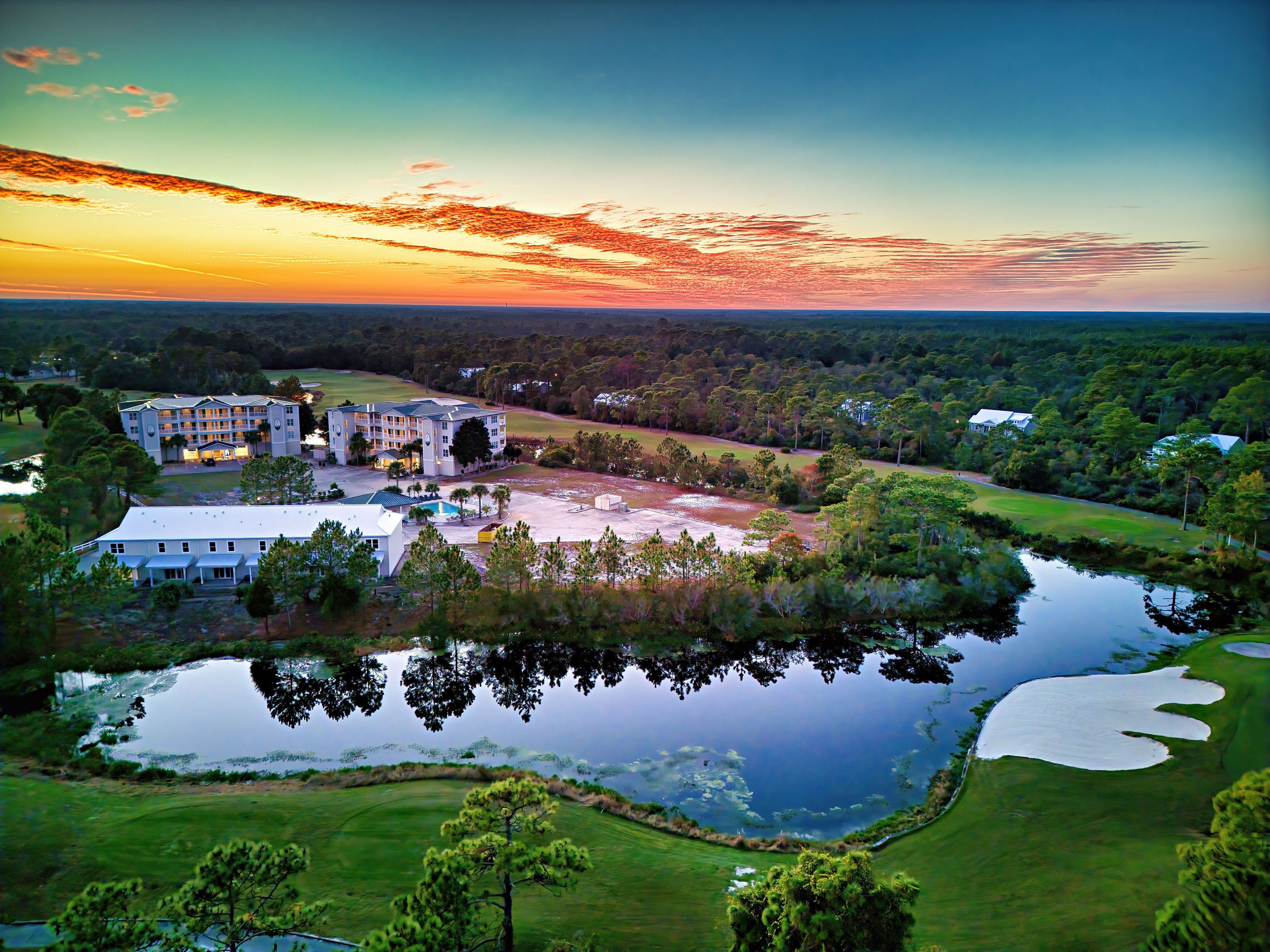 Un hotel grande con varias construcciones, un campo de golf y un lago.