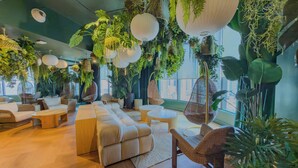 A modern lounge area with a sofa, chairs, hanging planters, and a view of the city. - F312B - Downtown Miami Cozy Studio with Pool & Gym (Miami)