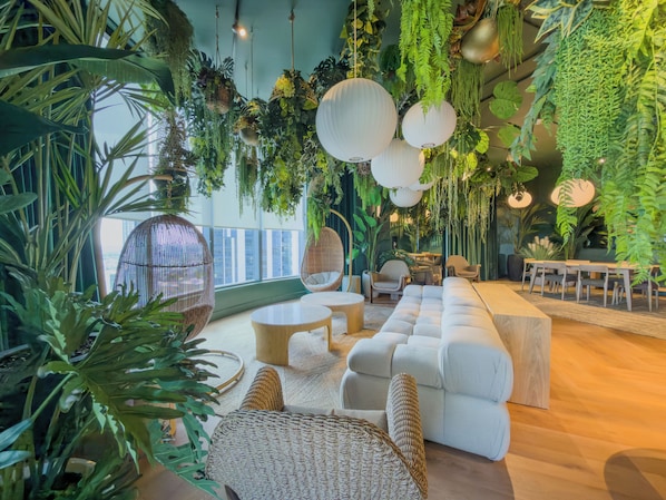 A modern interior with hanging plants, round tables, and a sofa. - F312B - Downtown Miami Cozy Studio with Pool & Gym (Miami)