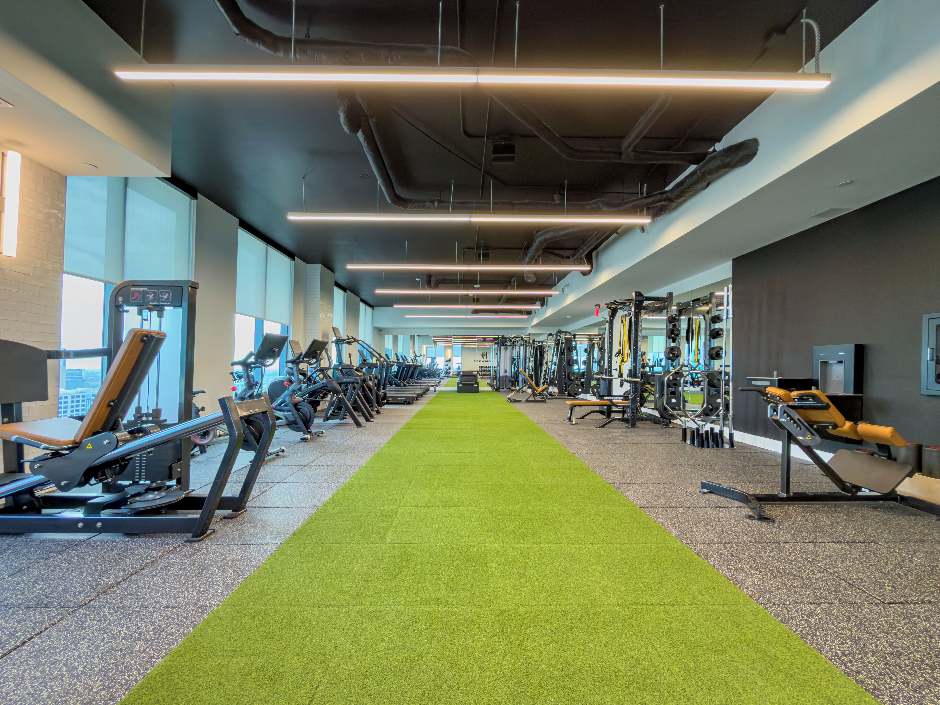 A gym with exercise equipment, a green carpet, and large windows.