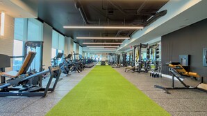 A gym with exercise equipment, a green carpet, and large windows. - F312B - Downtown Miami Cozy Studio with Pool & Gym (Miami)