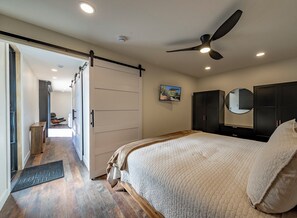 Ein Schlafzimmer mit einem Bett, einem Deckenventilator, einem Kleiderschrank und einer Tür zu einem anderen Raum.