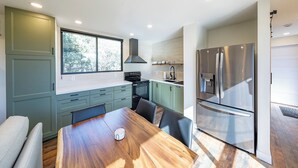 Eine moderne Küche mit Esstisch, Stühlen, Herd und Kühlschrank.