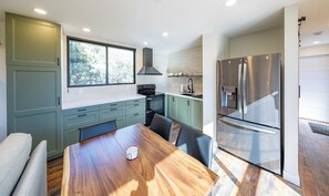 Eine moderne Küche mit Esstisch, Stühlen, Herd und Kühlschrank.
