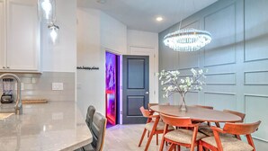 A modern kitchen with a built-in dishwasher, a dining area with a round table and chairs, and a chandelier. - Luxury Townhouse w/ Private Pool Near Disney & Universal (Orlando)