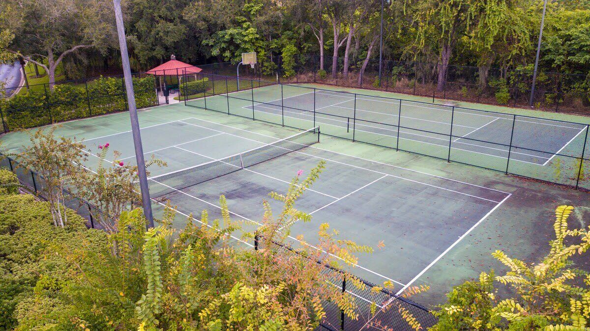 A tennis court surrounded by trees and a gazebo.