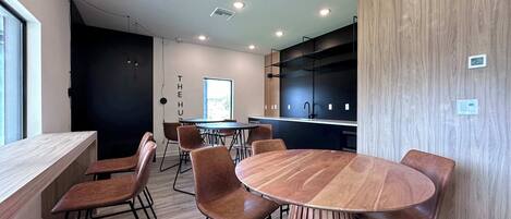 A modern kitchen with black cabinets, a wooden dining table, and six chairs.