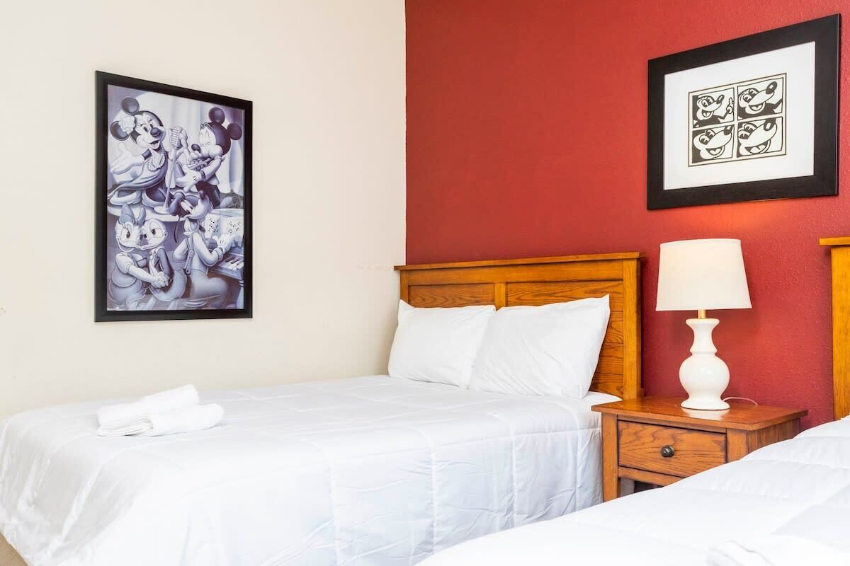 Een hotelkamer met een bed, een nachtkastje met een lamp en twee ingelijste foto’s aan de muur.