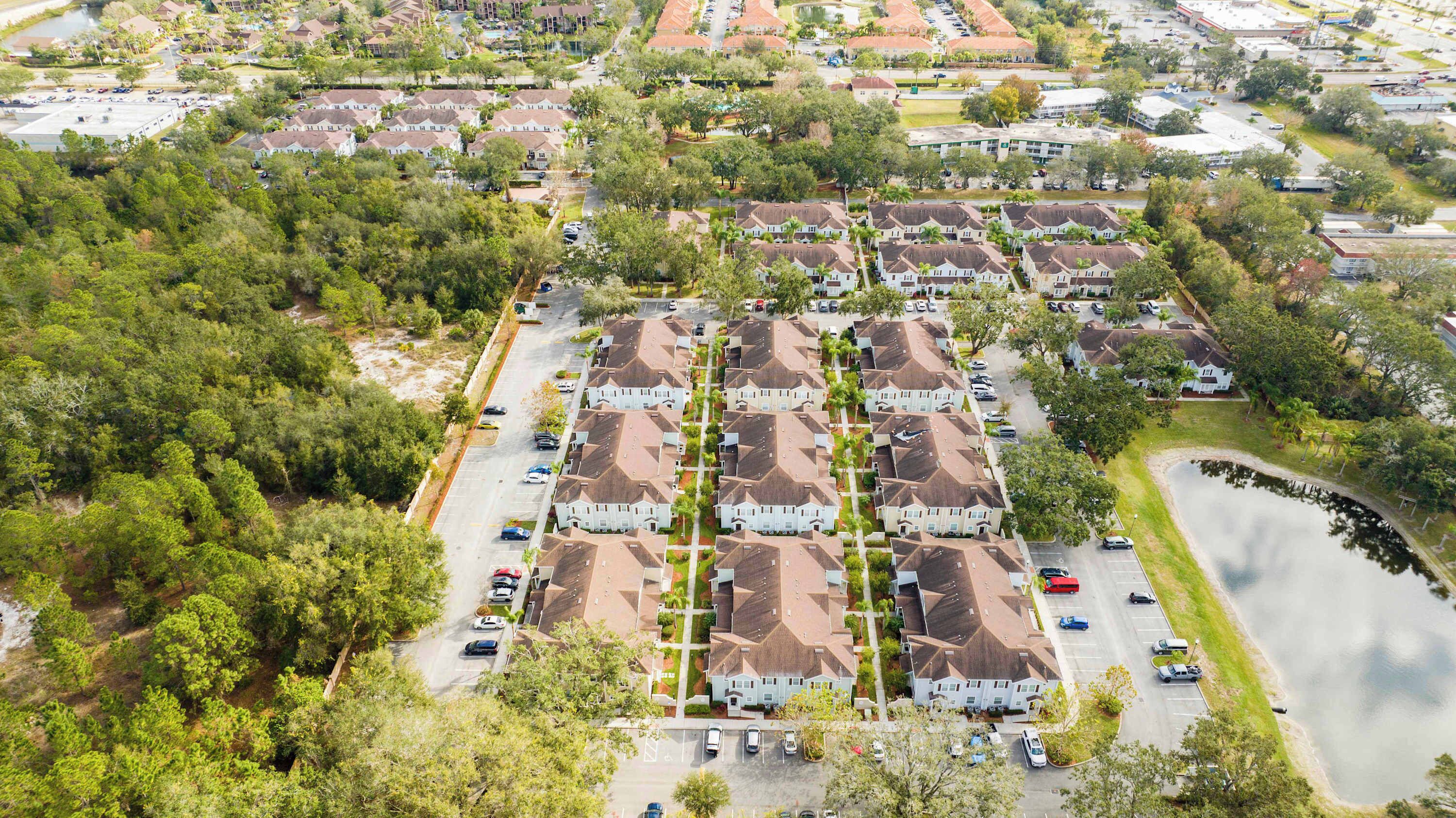 Een woonwijk met meerdere twee-onder-een-kapwoningen, een parkeerplaats en een waterpartij.