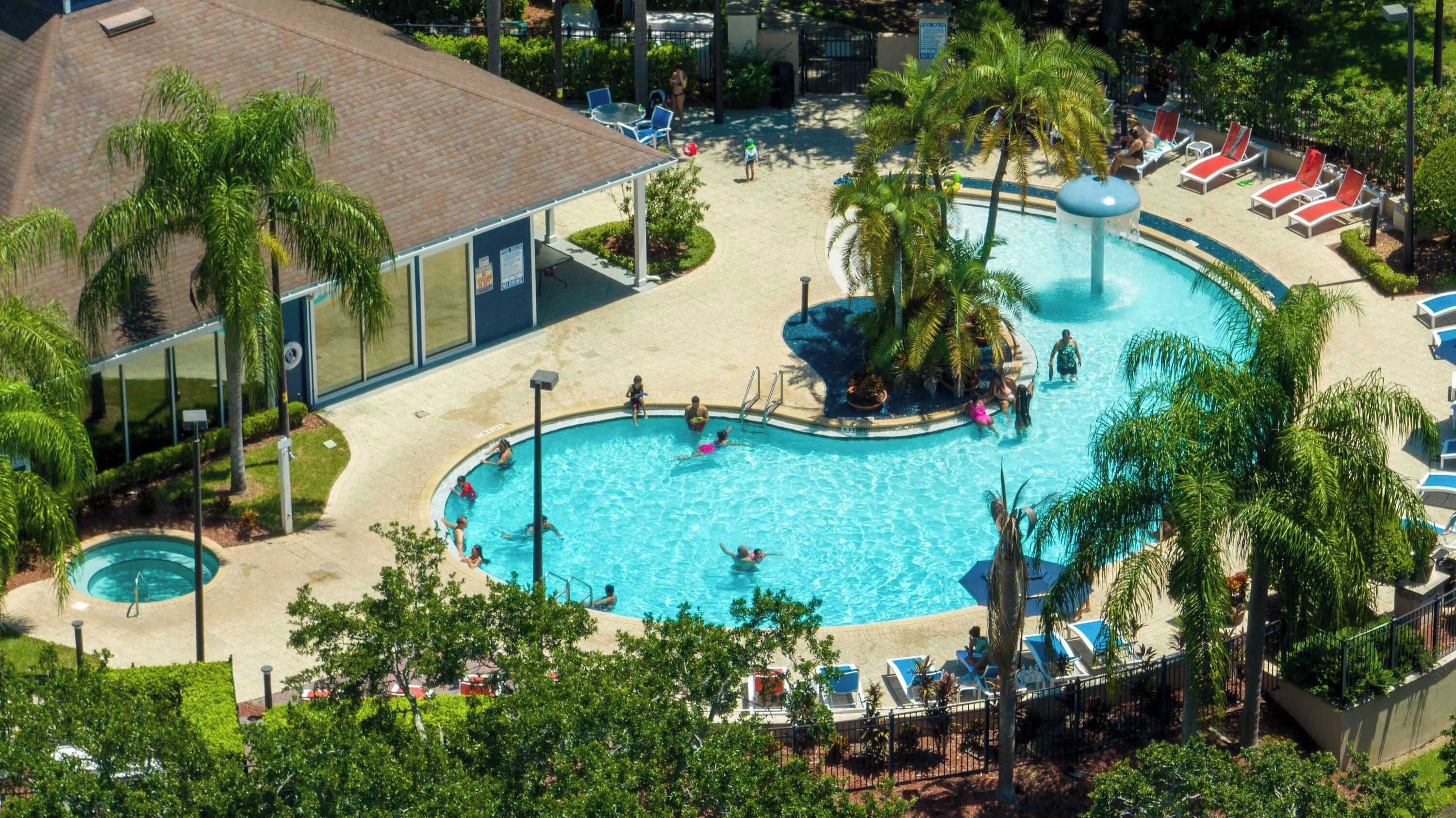 A large outdoor swimming pool surrounded by palm trees and lounge chairs.