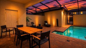 An indoor swimming pool with a glass ceiling, a wooden table with chairs, and a door. - Windsor Westside Resort Townhouse w/ Pool & Fast Wifi (Kissimmee)