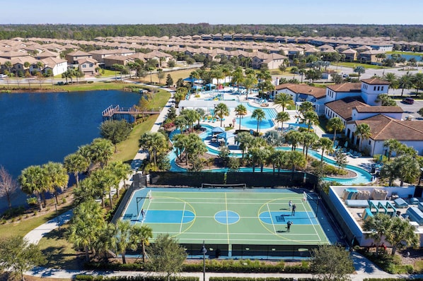 A residential area with a large swimming pool, tennis courts, and a lake.