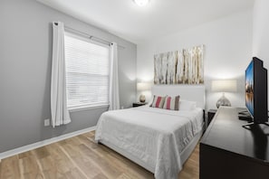 A modern bedroom with a bed, a TV, and artwork on the wall.