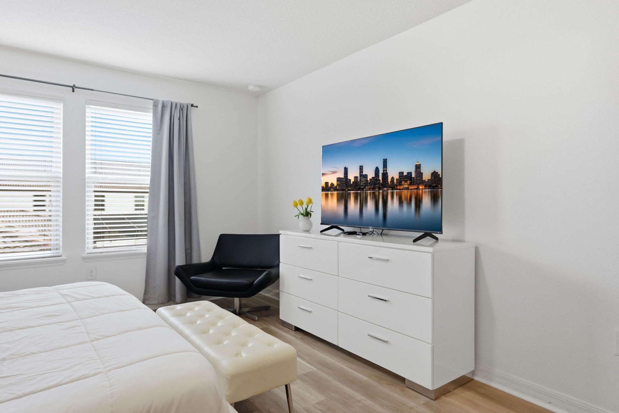 Una camera d'albergo con un letto, una scrivania, una sedia, una televisione e vista sulla città.