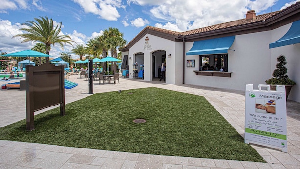 A courtyard with a bar/lounge area, palm trees, and a sign for massage services. - Windsor Westside Resort Townhouse w/ Pool & Fast Wifi (Kissimmee)