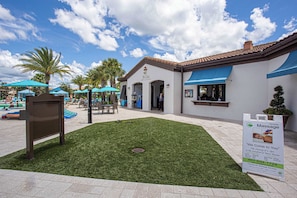 A courtyard with a bar/lounge area, palm trees, and a sign for massage services.