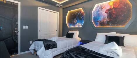 Un dormitorio con dos camas, un escritorio y un techo decorado con un diseño de estrellas.
